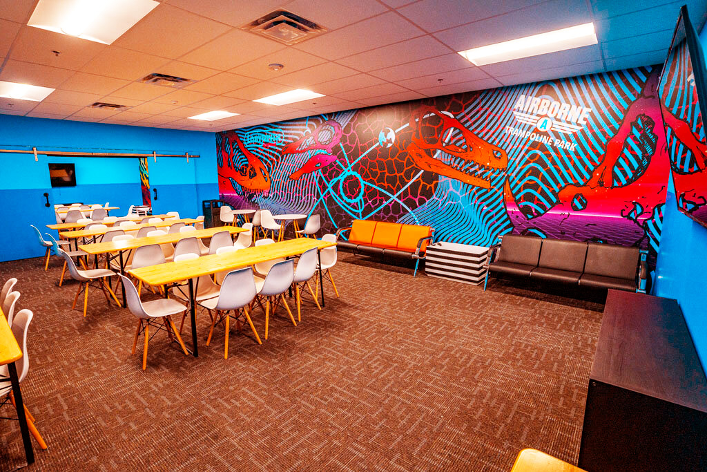 A spacious room filled with tables and chairs, inviting people to gather and engage in various activities at Airborne trampoline park.